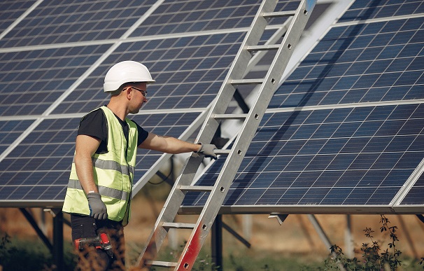 Man in a white helmet near a solar panel